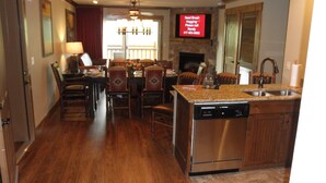 A kitchen with a dishwasher, a dining area with chairs and a table, and a TV displaying a message.