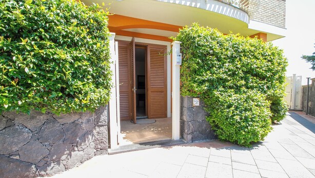 Une entrée en pierre avec une porte en bois, un chemin pavé de pierres et une haie bien entretenue.