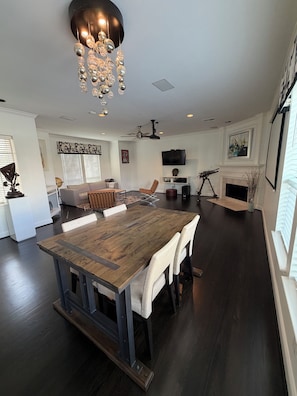 A spacious living area with a large wooden dining table, a ceiling fan, and a fireplace.
