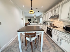 A modern kitchen with white cabinetry, a central island, and a dining area with chairs.