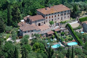 An aerial view of a large stone building with multiple windows and a tiled roof, surrounded by lush greenery and a swimming pool. - Ricetro villa with private pool and hot tub (Licetro)