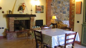 A cozy living room with a fireplace, a television, and a dining table set for four. - Ricetro villa with private pool and hot tub (Licetro)
