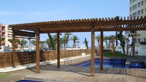 A rooftop pool area with wooden pergolas and a wooden deck. - FRENTE AL MAR, WIFI, 130M2 (Empuriabrava)