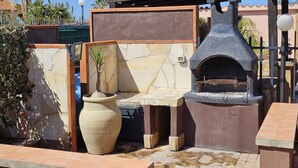 An outdoor patio area with a stone oven, a large vase, and a pergola structure.