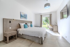 Ein modernes Schlafzimmer mit einem großen Bett, Nachttischen, einem Schreibtisch und einem Fenster mit Vorhängen.