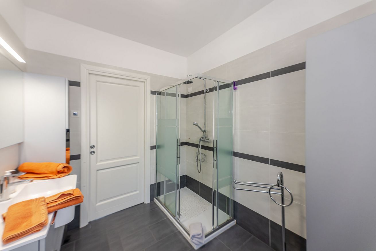 Ein modernes Badezimmer mit einer gläsernen Dusche, weißen Fliesen und einem Handtuchhalter.