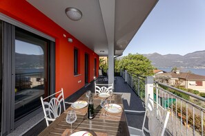 A balcony with a table set for two, overlooking a scenic view of mountains and a lake.