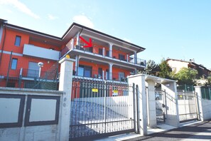 A multi-story building with a gated entrance, balconies, and a clear sky.