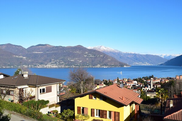 A coastal town with houses, a clear blue lake, and mountains in the background.