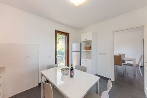 Una cocina moderna con una mesa de comedor, sillas, un refrigerador y un ventanal.