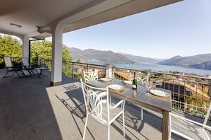 A terrace with a table set for two, overlooking a lake and mountains.