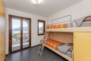 A room with a bunk bed, a ladder, a view through a glass door, and a wooden cabinet.