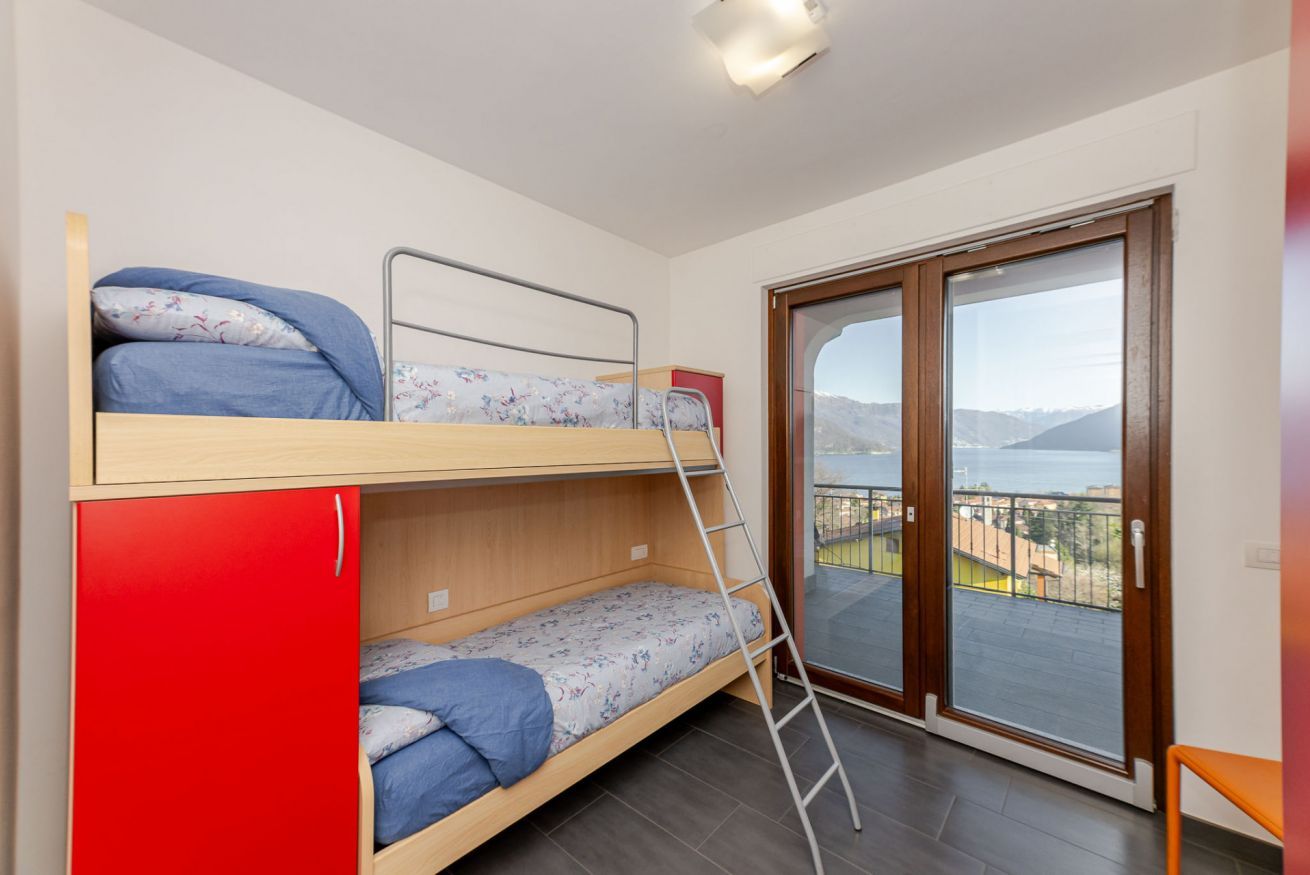 Et værelse med køjeseng, et rødt skab, en stige og en balkon med udsigt.