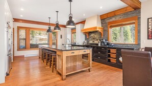 A spacious kitchen with a central island, wooden beams, and large windows. - Upscale Ski In/Out Duplex on The Ridge with Garage, Private Hot Tub, laundry (Silver Star Mountain)