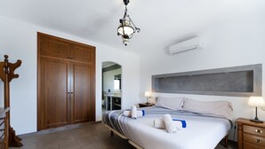 A neatly arranged bedroom with a bed, bedside tables, a wardrobe, and a hanging light fixture. - Finca Cas Mungi, Villa with Private Pool (Horta, S' (Felanitx))
