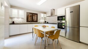 A modern kitchen with white cabinets, a stainless steel refrigerator, a microwave, and a dining table with yellow chairs. - Finca Cas Mungi, Villa with Private Pool (Horta, S' (Felanitx))