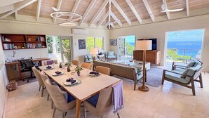 A spacious room with a high ceiling, a dining area with a table set for four, a sofa, and a television.