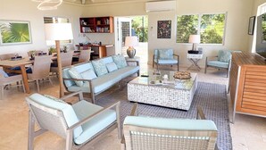 A spacious living area with a sofa, chairs, a coffee table, and a bookshelf.