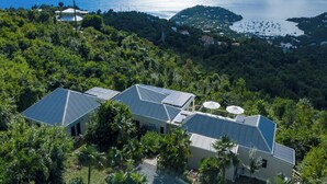 A coastal property with multiple buildings, solar panels, and lush greenery.