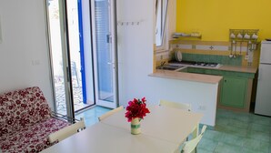 Eine kompakte Küche mit Essbereich, einer Couch und einem Tisch mit Blumen.