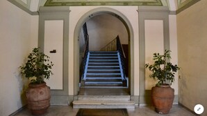 A grand staircase with a blue handrail, flanked by two large terracotta pots with plants.