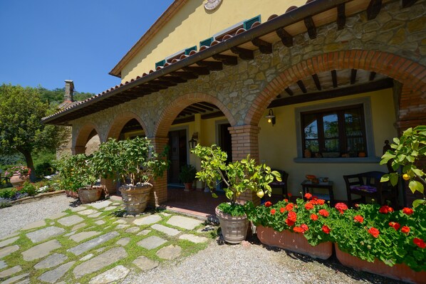 A building with a stone facade, multiple arches, and potted plants.