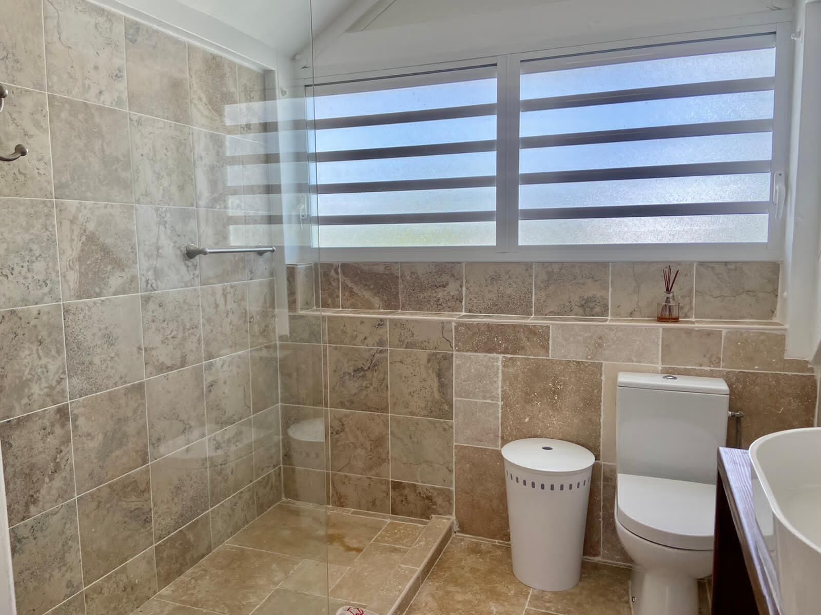 A bathroom with a shower, toilet, and window.