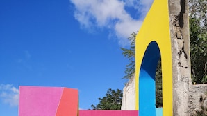Una escalera colorida que lleva a una puerta, con un cielo azul despejado al fondo.