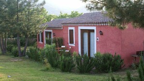 Un edificio rojo con techo de tejas, una puerta y ventanas. Hay una mesa y sillas afuera.