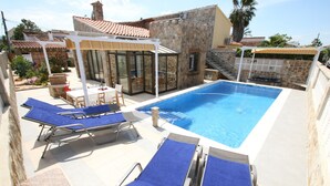 Ein Swimmingpool mit Liegestühlen und einer überdachten Terrasse.