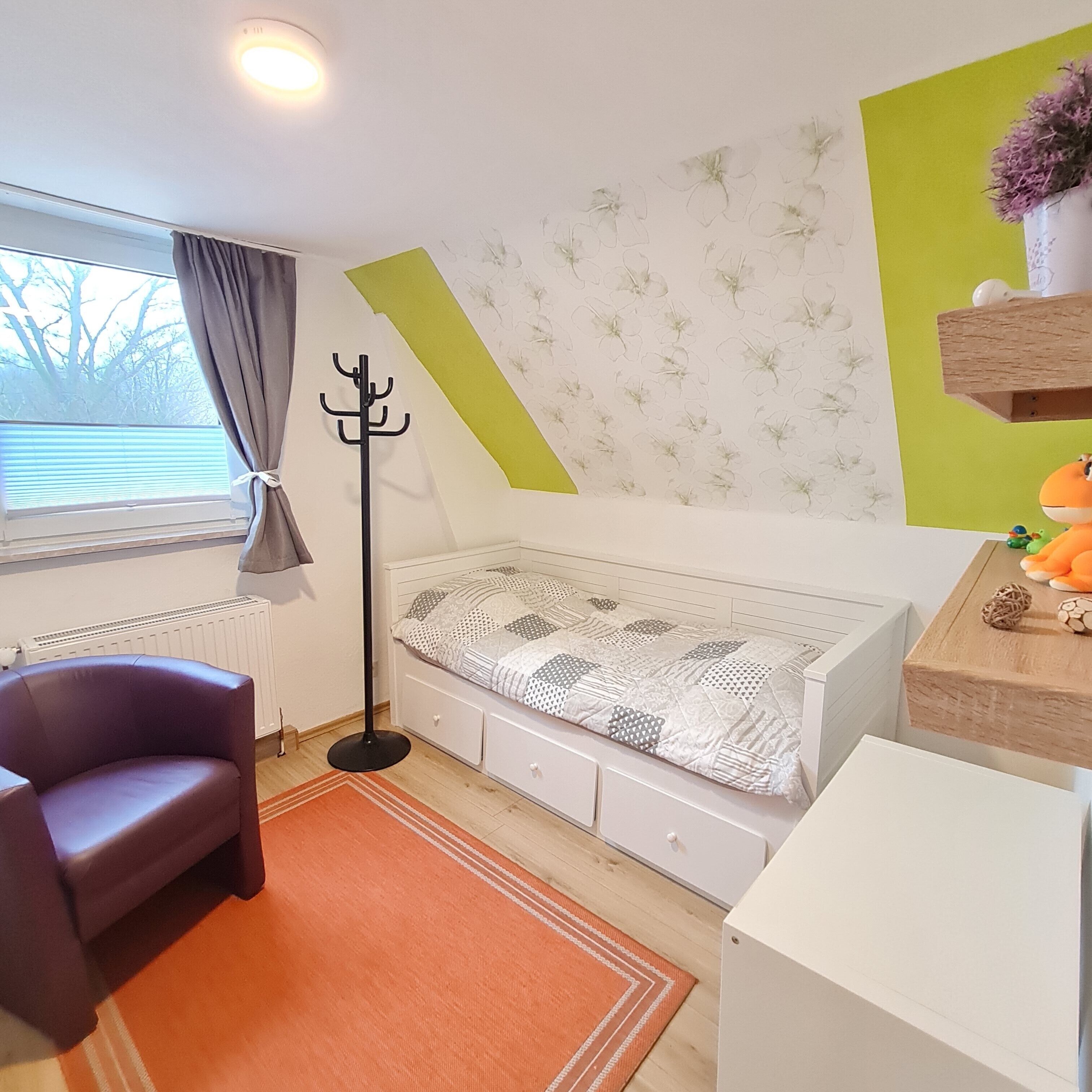 Habitación infantil con literas, un escritorio, una silla y un radiador.