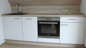 A modern kitchen with a built-in oven, a sink, and a light above the countertop. - Apartment with terrace and best conditions for restful sleep (Dahme)