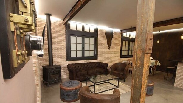 Uma sala de estar aconchegante com parede de tijolos, um sofá, uma mesa de centro e um fogão antigo.