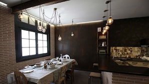 Uma sala de jantar com parede de tijolos, uma janela grande e um espaço de bar com painel de azulejos.