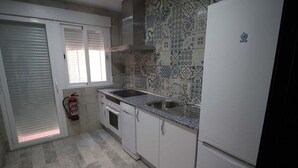 Een keuken met witte kastjes, een granieten aanrechtblad, een roestvrijstalen spoelbak en een decoratieve spatwand.