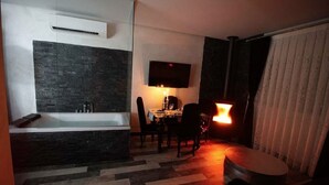 Een moderne badkamer met een bad, een douche en een wastafel met spiegel. Er is een eethoek met een tafel en stoelen, en een klein rond tafeltje met een lamp.