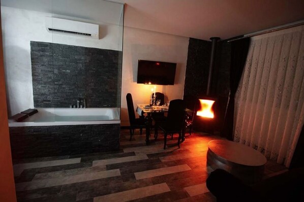 A modern bathroom with a bathtub, a shower area, and a vanity with a mirror. There is a dining area with a table and chairs, and a small round table with a lamp. - La Perla Negra Rural Apartment (Guadalajara)