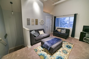 A living room with two sofas, a coffee table, and a patterned rug. There are wall decorations and a window with curtains. - 2 bedroom, Across from the YMCA (Fish Creek)