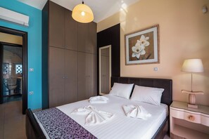 A hotel room with a bed, a nightstand, a lamp, a painting, and a wardrobe. - Paramithia Villa with Private Pool (Afantou)