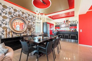 A modern kitchen with red accents, a dining area with a large table and chairs, and a decorative mirror on the wall. - Paramithia Villa with Private Pool (Afantou)