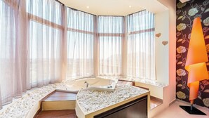 Een moderne badkamer met een ruim bad, een wastafel met een marmeren blad en een decoratieve wand met een bloemendesign.