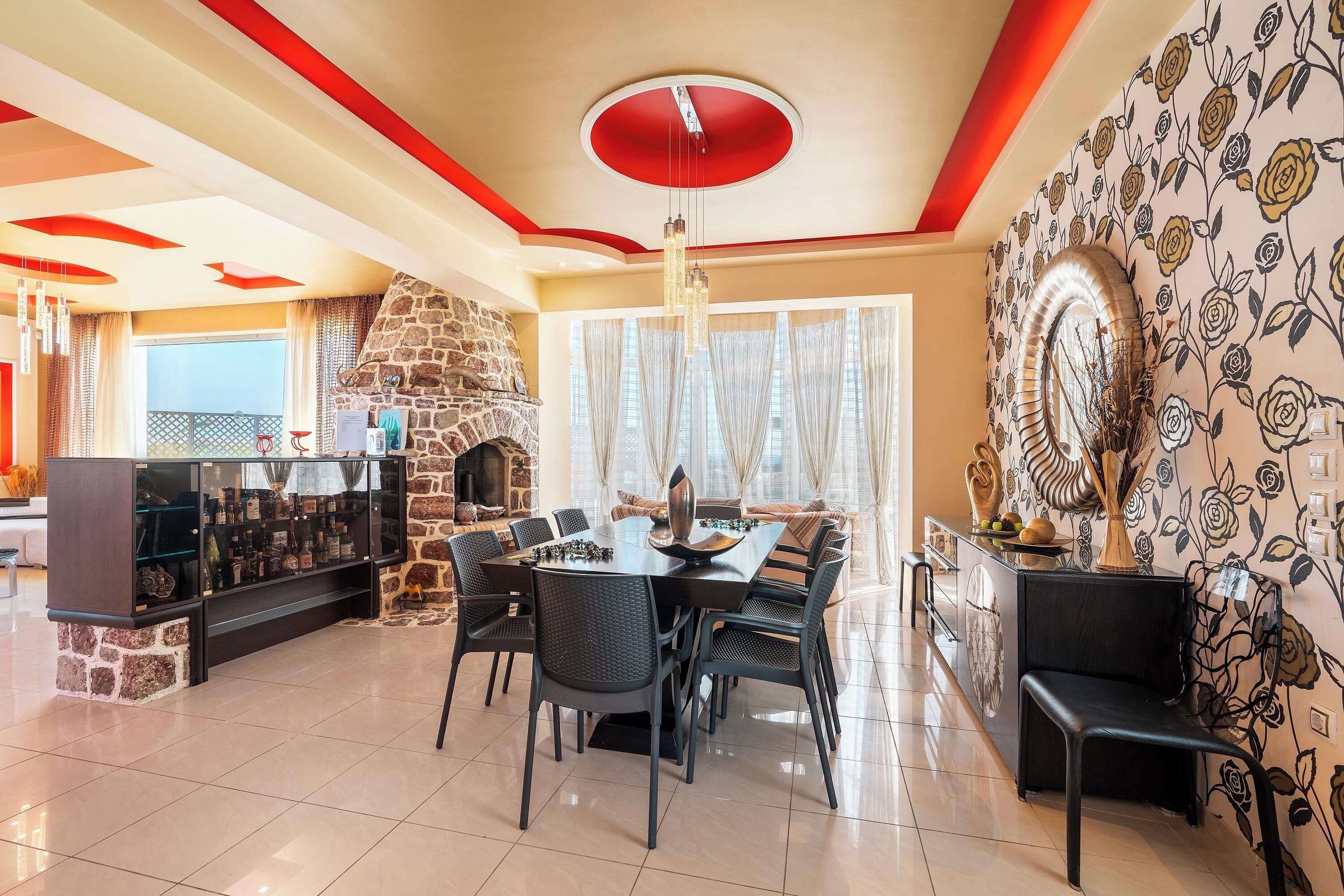 Uma sala de jantar com lareira de pedra, um candelabro e papel de parede floral.