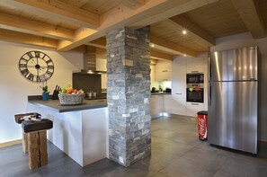 A modern kitchen with a stone pillar, a large clock, a Samsung refrigerator, and a basket of fruit on the counter. - Large apartment for 14 people in Chatel centre - Chatel Reservation (Châtel)