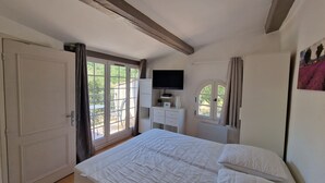 A bedroom with a bed, a TV, a dresser, and a window with curtains. - Hameau des Claudins # 2 Préconil with heated swimming pool near Saint-Tropez (Le Plan-De-La-Tour)