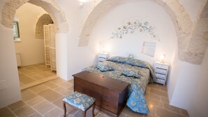 Un dormitorio con cama, mesitas de noche, cómoda y un arco de entrada.