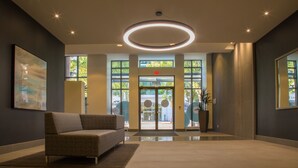 A modern lobby with a sofa, a circular light fixture, and a glass door entrance. - EraBella-Downtown 12th floor Beauty, Free Parking and Wifi, Close to Everything by Victoria Prime! (Victoria)