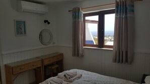 A bedroom with a bed, a wooden desk, a mirror, and a window with curtains. - Amazing panoramic sea views!!!  (Playa Blanca)