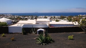 A coastal residential area with white buildings, some with flat roofs and solar panels, and a clear view of the sea and distant mountains. - Amazing panoramic sea views!!!  (Playa Blanca)