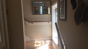 A staircase with wooden steps and white handrails, leading to a landing with a small mirror and a framed picture on the wall.