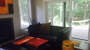 A living room with a black leather sofa, a red tray, and a decorative stool.